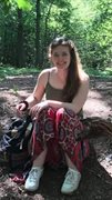 Maddi Maya, sitting smiling in a forest